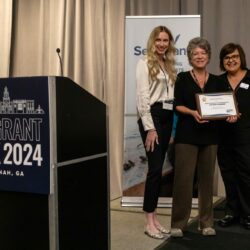 Science communicator Marie Zhuikov poses with a communications award at Sea Grant Week alongside two other people