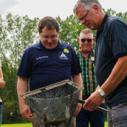 Fish farmer doug Sackett nets several perch from him pond as the tour group watches