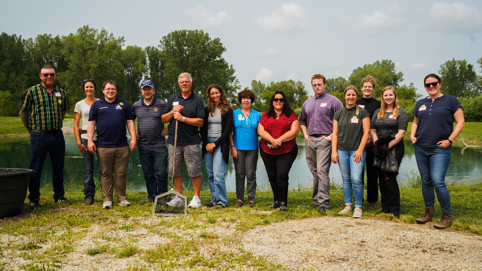 The tour group stands in front of an outdoor pond