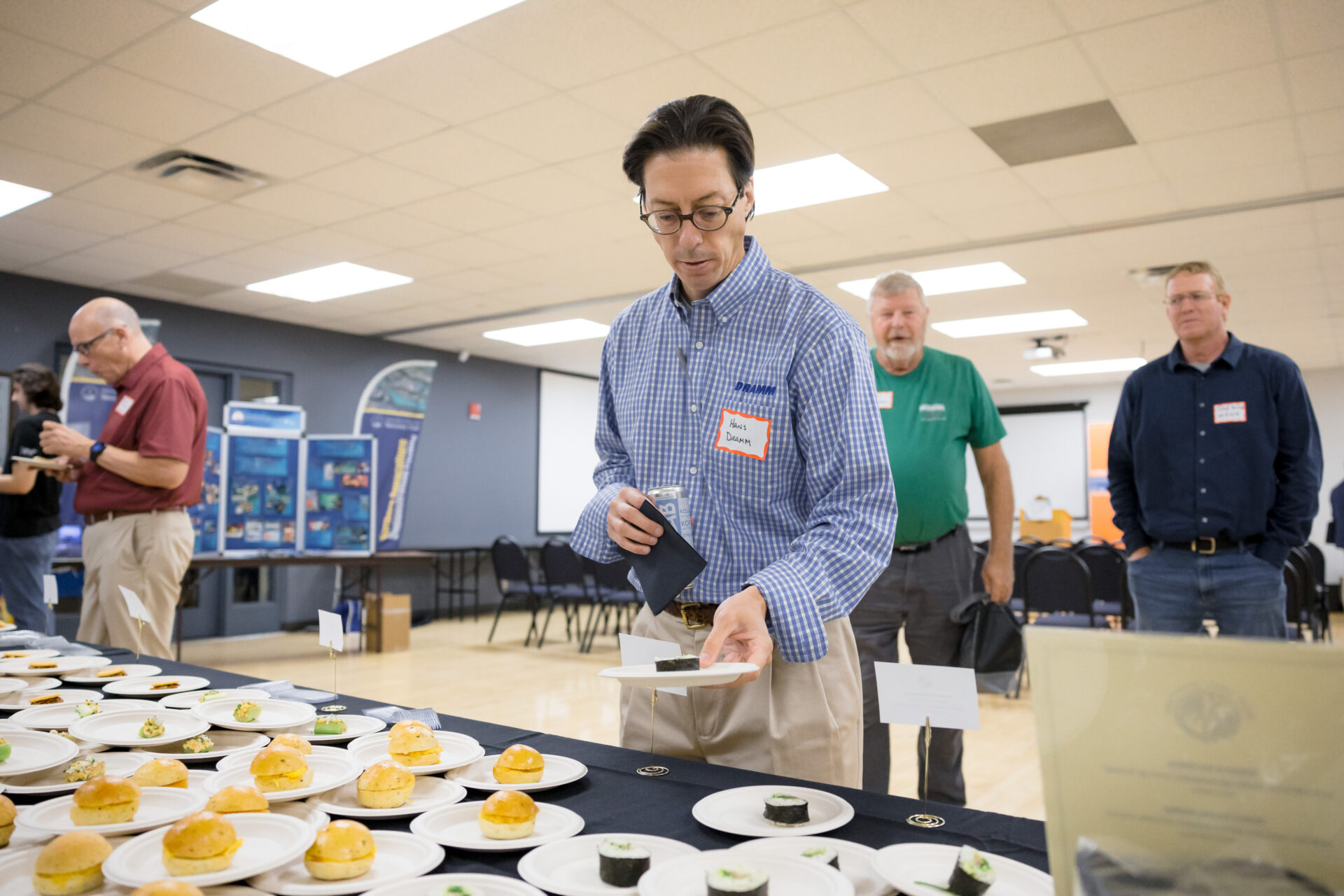 A participant picks up a small plate of pickled herring kimbap.