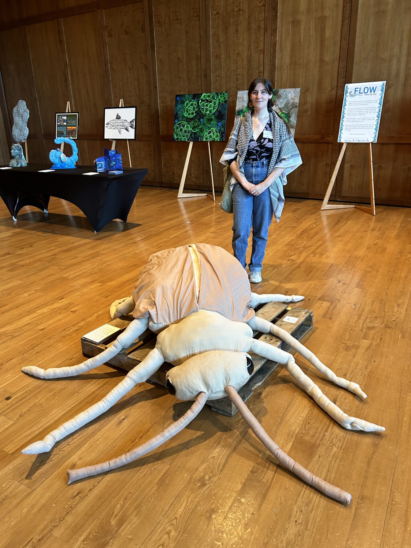 FLOW artist Astrid stands next to her creation: a 5 foot beige beetle stuffed animal