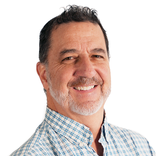 A headshot of Andrew Savagian smiling, wearing a collared shirt.