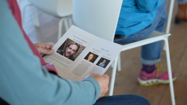 A person reading the biographies of the play wright and the cast of actors