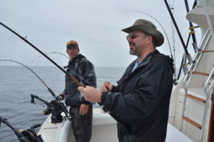 Two anglers on a boat holding fishing rods