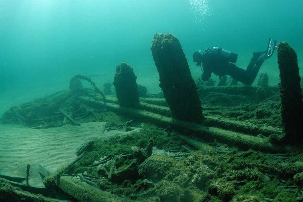 A scuba diver swims along a shipwreck lying on the bottom of the Lake Michigan.